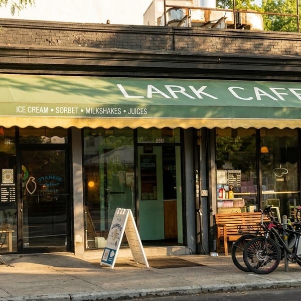 Exterior of Lark Cafe with a green awning, outdoor seating, and bicycles parked outside.